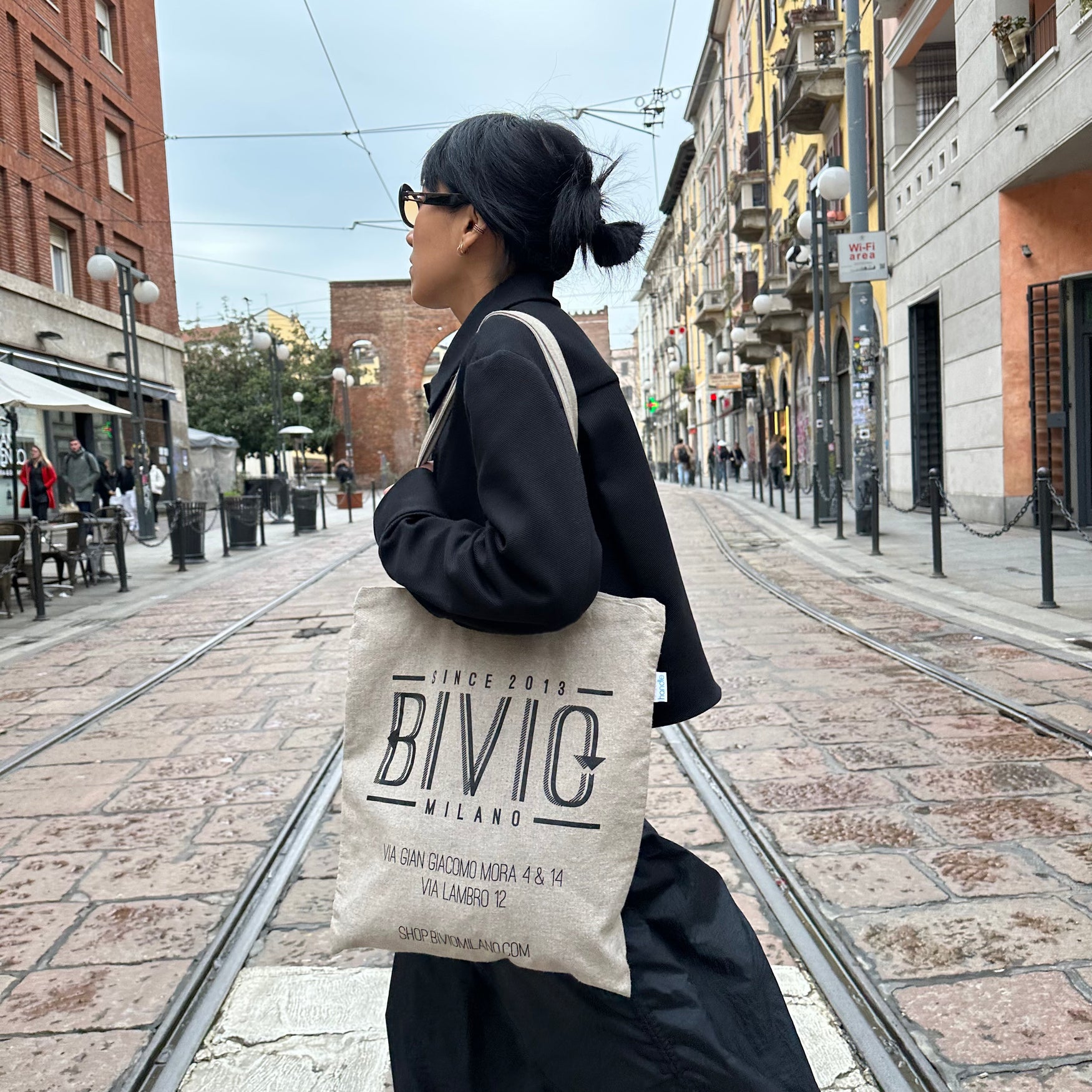 foto di una ragazza che cammina con indosso la Bivio bag- borsa in tela con logo del negozio